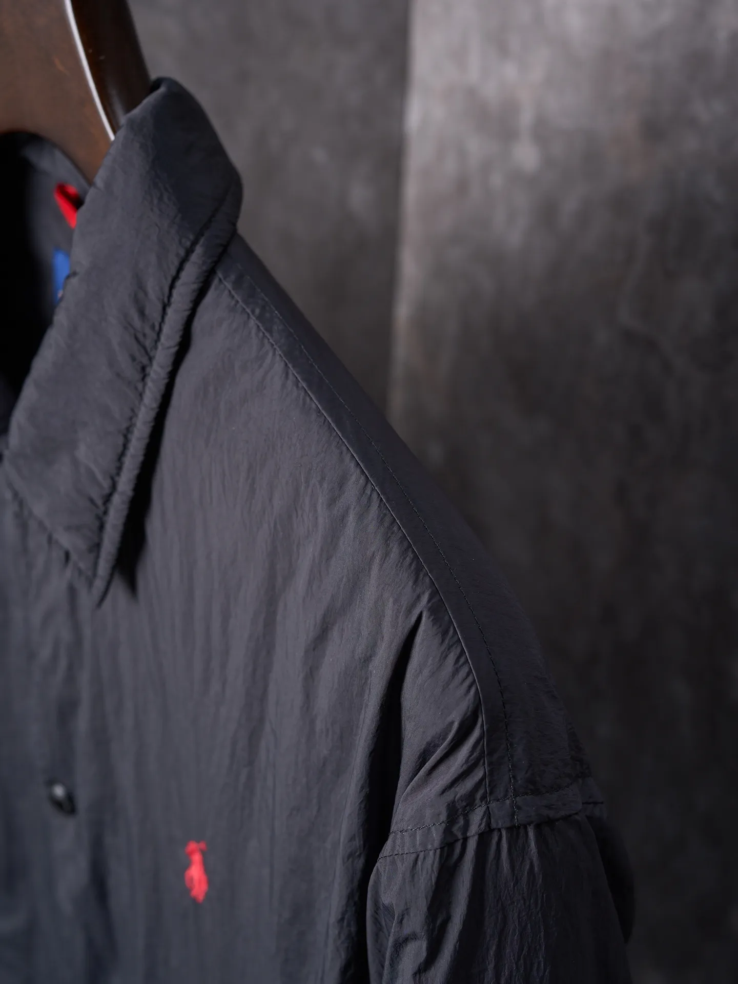 P640 Actual auction] Ralph Lauren/Ralph Lauren Pony Red Label lightweight cotton lapel coach jacket [Ready stock] S M L XL Material: high-density nylon taffeta Features: Density is about 210T-300T, smooth and slightly matte surface, excellent windproof and waterproof performance (with DWR water-repellent treatment), strong wrinkle resistance and easy care, in line with the positioning of American casual "durable and practical".  Color: Classic dark black, using vat dyeing process (dye penetrates into the fiber), the color fastness reaches ISO level 4 or above to avoid fading or color transfer after washing.  2. Lining fabric Material: Lightweight cotton-polyester blended lining (65% Polyester + 35% Cotton) Function: Reduce friction between the fabric and inner clothing, improve wearing smoothness; blended material has both breathability and durability to avoid the stuffy feeling of pure nylon lining.  Version and cutting process Version: Classic Coach Jacket, loose version, slightly dropped shoulder line (shoulder width is 1-2cm wider than the standard version), length to the hips, and slightly tapered straight sleeves, taking into account both freedom of movement and casual style. Embroidery technology: Polo horse logo on the left chest: flat satin stitch embroidery (satin embroidery), embroidery thread: 100% polyester high color fastness embroidery thread (the color number is consistent with the brand’s standard red color card), stitch density 12-15 stitches/cm, the outline of the horse logo is clear, and the details of the rider and horse are burr-free.  Embroidery positioning: precise positioning through the template (12cm from the neckline and 8cm from the placket) to ensure left and right symmetry and centering.  Topstitching technology: The seams of the body are made of double-needle flat seams (needle pitch 3cm/10 needles), the stitches are smooth and straight, the stitching color is dark black (the same color as the fabric), and the stitch width is 0.5cm, which enhances firmness while forming simple decorative lines.  1. Main body splicing, splicing of the front placket and body: The placket is made of double-layer folding + flat seam splicing, with a thickness of about 0.3cm to ensure that the buttons are not easily deformed when fixed; the edges of the placket are cut with a hot knife to avoid burrs.  Sleeve panels are spliced ​​to the body: the armholes are spliced ​​with round-head keyhole machine seams + flat seams. After splicing, the armholes have a natural curvature and no sense of tightness during movement; the height of the sleeves is about 8-10cm, which is in line with the loose characteristics of casual jackets.  Main button: black urea resin button, matte surface treatment, buttonholes are hand-made keyholes (6 strands of cotton thread, keyhole density 8 stitches/mm), the edges of the eyelets are smooth and without burrs.  Collar buttons: The first button on the collar is a hidden button (diameter 12mm), which prevents the collar from opening and improves the neatness of wearing.